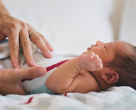 Parent gently holding a newborn baby's feet